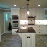 Modern kitchen with white cabinets, a central island, stainless steel appliances, and tile flooring.
