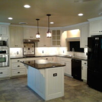 Modern kitchen with white cabinets, black appliances, tile floor, center island, and pendant lights over the island.