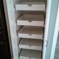 User comments A tall cabinet with five empty white pull-out shelves is shown open next to a refrigerator in a kitchen.