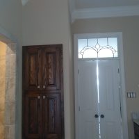 Double doors with frosted glass, dark wood cabinets, and a tiled shower in a neutral-toned bathroom.