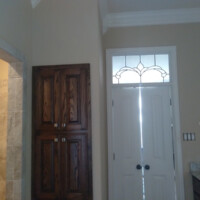 Double doors with frosted glass, dark wood cabinets, and a tiled shower in a neutral-toned bathroom.