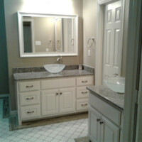 Bathroom with white cabinets, granite countertops, vessel sinks, and a large mirror above the main vanity.