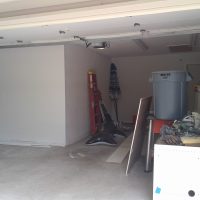 User comments A garage with open doors, containing a red ladder, trash bin, tools, and miscellaneous items scattered around.