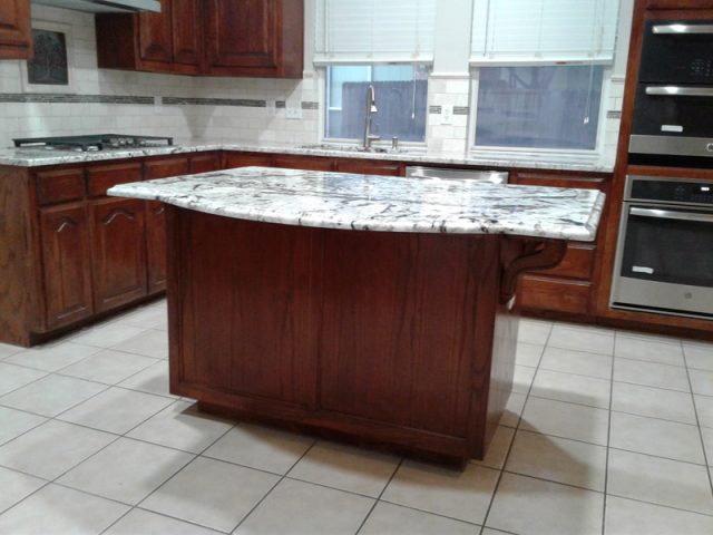 User comments Kitchen with a marble-topped island, wooden cabinets, tiled floor, and stainless steel appliances.