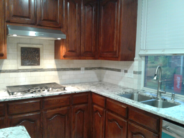 Kitchen with dark wood cabinets, granite countertops, a gas cooktop, and a double sink beneath a window with blinds.