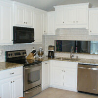 Modern kitchen with white cabinets, stainless steel appliances, granite countertops, and white subway tile backsplash.