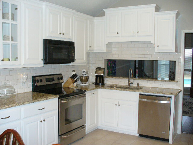 Modern kitchen with white cabinets, stainless steel appliances, granite countertops, and subway tile backsplash.